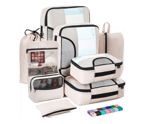 A collection of beige travel packing cubes and bags, including various sizes and a clear pouch for organization.
